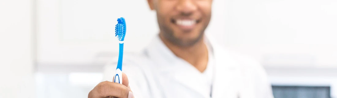 Dentist Milpitas CA A Dentist Holds a Blue Toothbrush out Toward the Camera Dental Care Focused A Dentist Holds a Blue Toothbrush out Toward the Camera